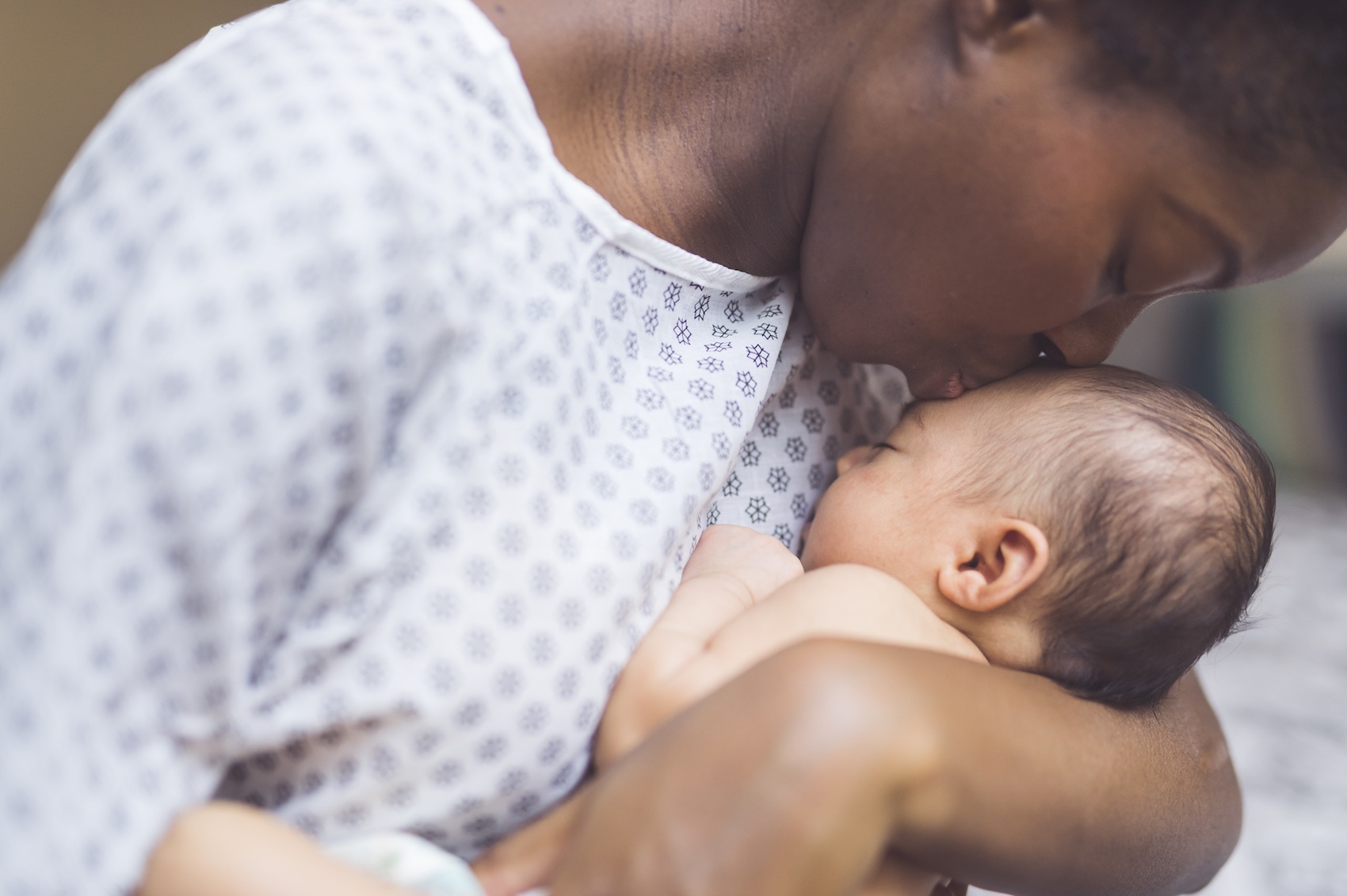 African American mother kissing newborn on forehead in a hospital