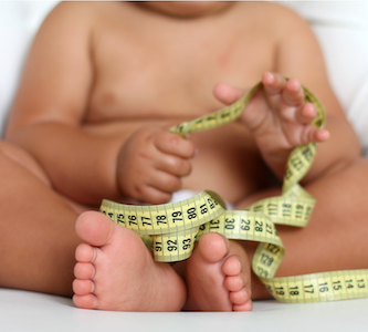 obese infant playing with measuring tape